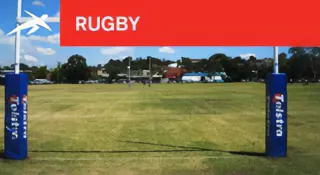 Sporting field with rugby goal posts and blue post padding. A red banner at the top reads “RUGBY” with HiTech’s logo.